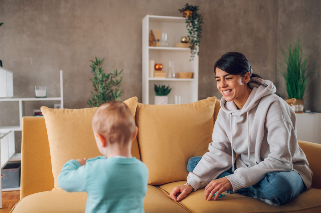 Mother sitting on a Sofa playing with her toddler with Montessori Toys.

