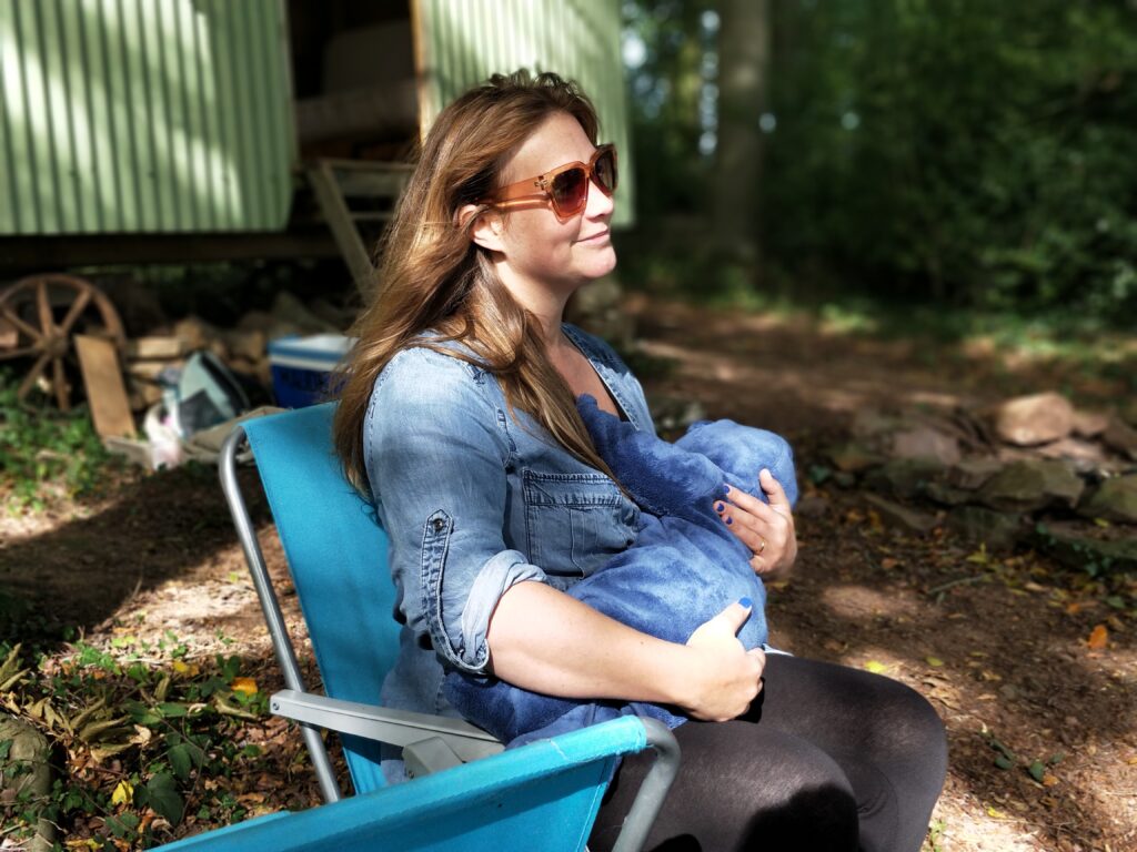 Mother breastfeeding her baby sitting on a lawn chair in the backyard.