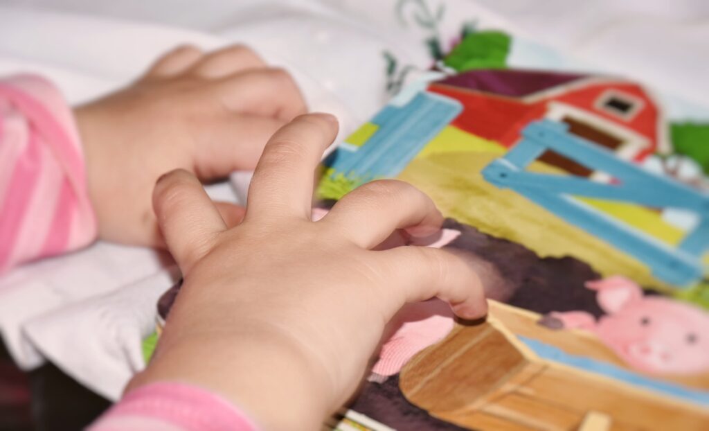 Small hands of a baby interacting with a Sensory Book about Farm Animals
