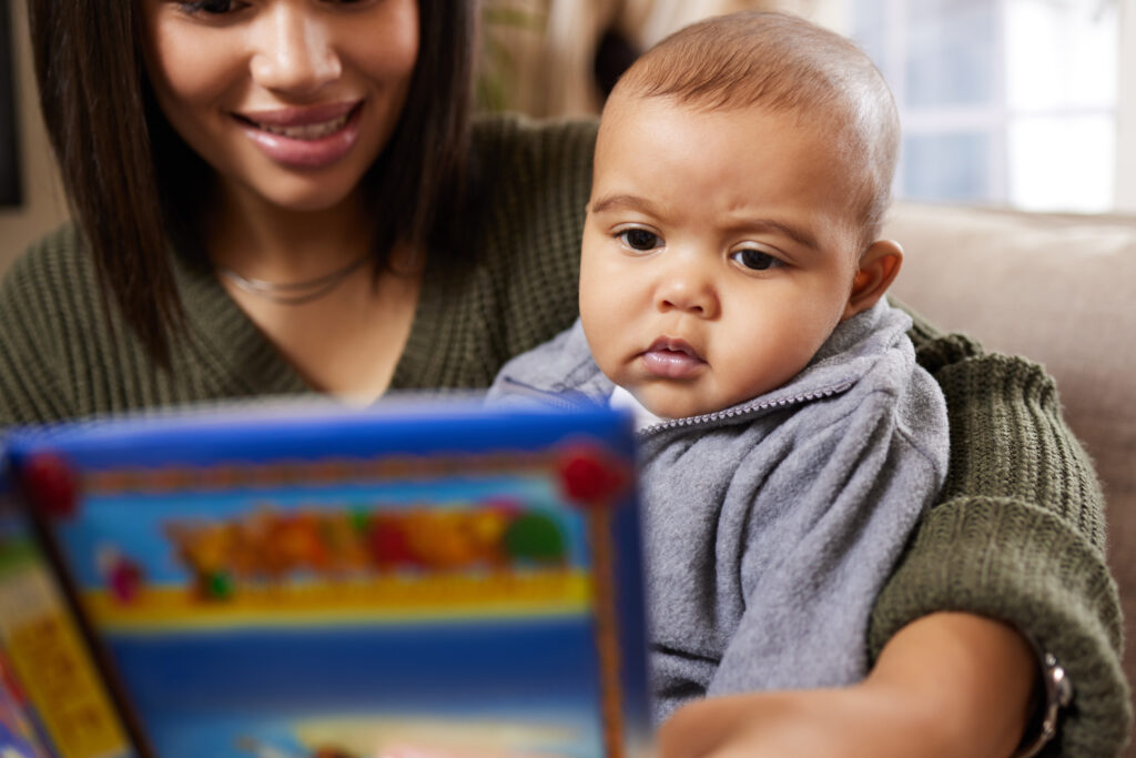 Mother looking at pictures in the book with her baby