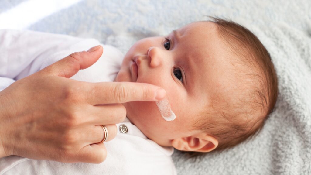 Apply Baby Sunscreen on the baby's cheeks.