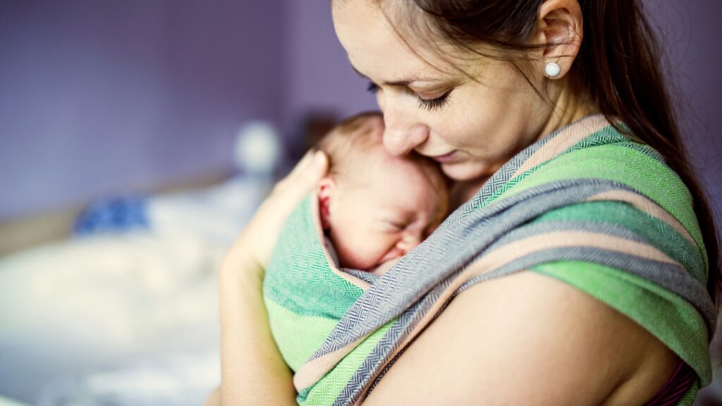 Mother holding her baby in a wrap baby carrier.