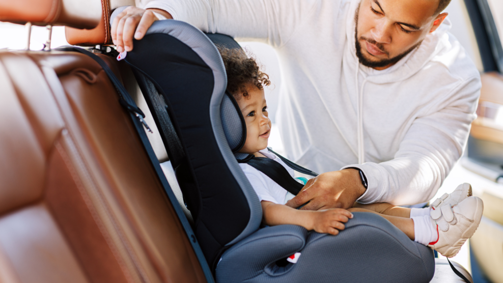 Baby Car Seats: A father placing his child in a front-facing car seat.